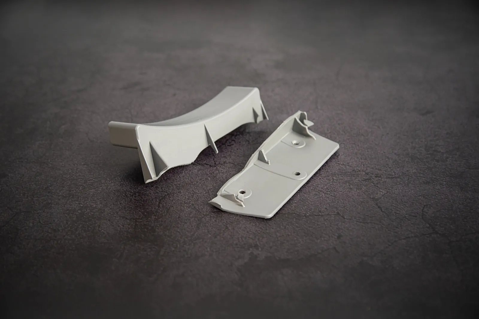 The broken original part, in two pieces, on the bench