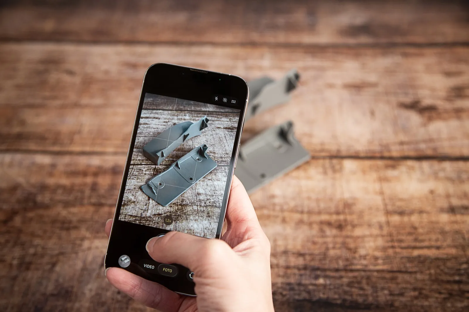 A phone photographing the broken part on a wooden table